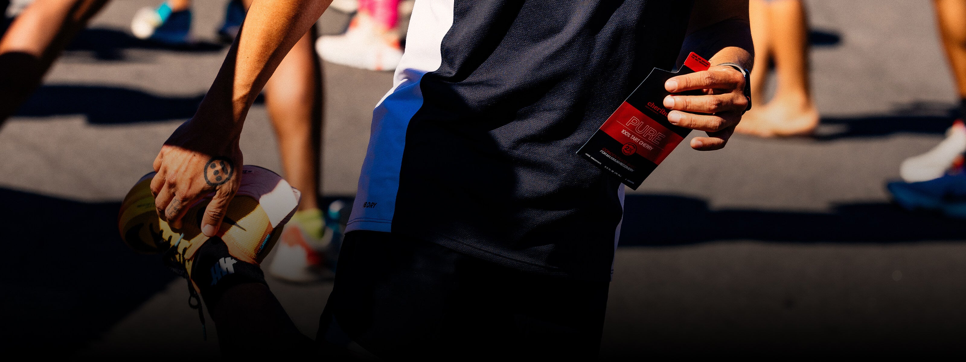 Runner stretching while holding a pouch of Pure Tart Cherrie