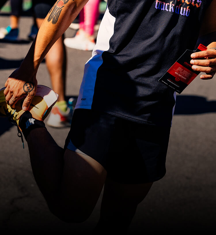 Runner stretching while holding a pouch of Pure Tart Cherrie